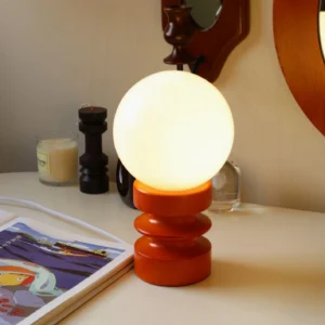 Contemporary table lamp with stacked wooden base illuminated on home office desk with decor