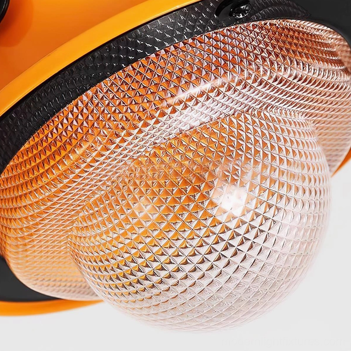 Close-up detail of diamond-patterned orange acrylic lampshade with exposed bulb and black metal trim