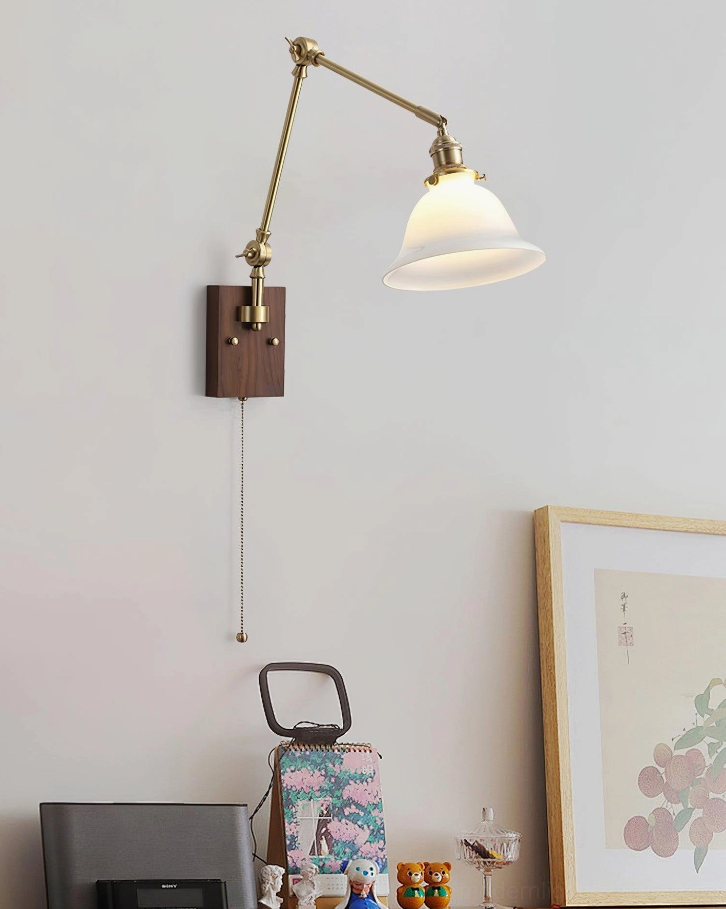 Adjustable brass swing arm wall sconce with green glass shade, walnut wood mount, and traditional pull chain switch for task and ambient lighting