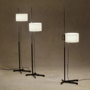 Set of three contemporary floor lamps with adjustable drum shades and cross metal bases displayed together in warm studio lighting