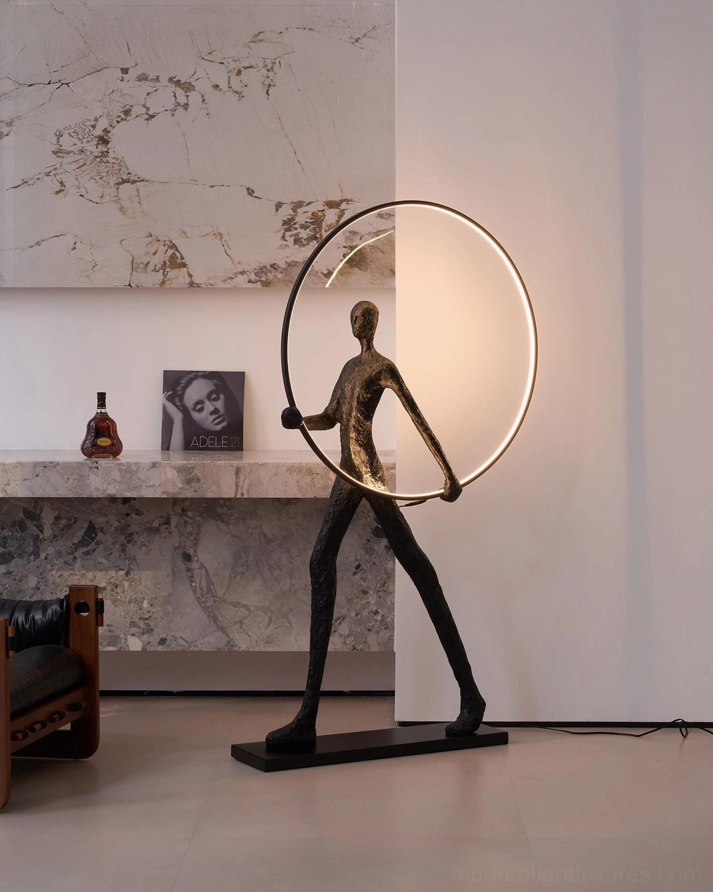 Minimalist geometric floor lamp with human sculpture figure and warm glowing circular light ring, side profile in living room