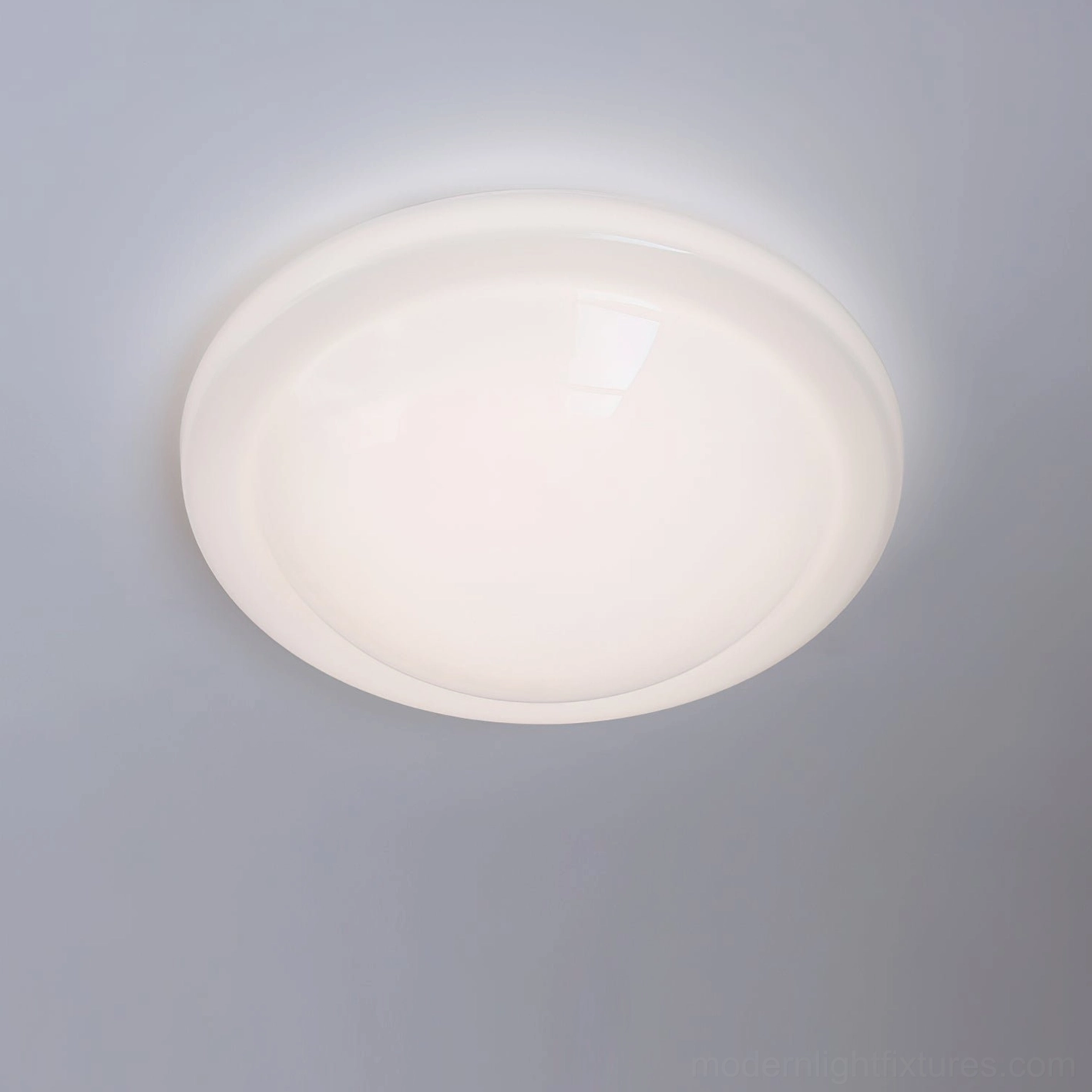 Aire flat round flush ceiling light fixture with opaque white full dome and slim metallic border in studio background