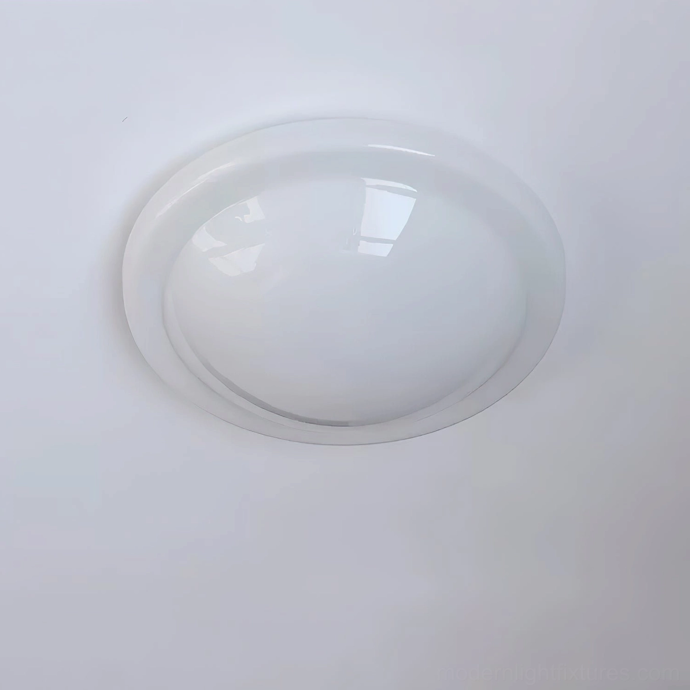 Aire recessed round flush ceiling light with clear glossy acrylic dome and thin metallic rim in minimalist studio setting