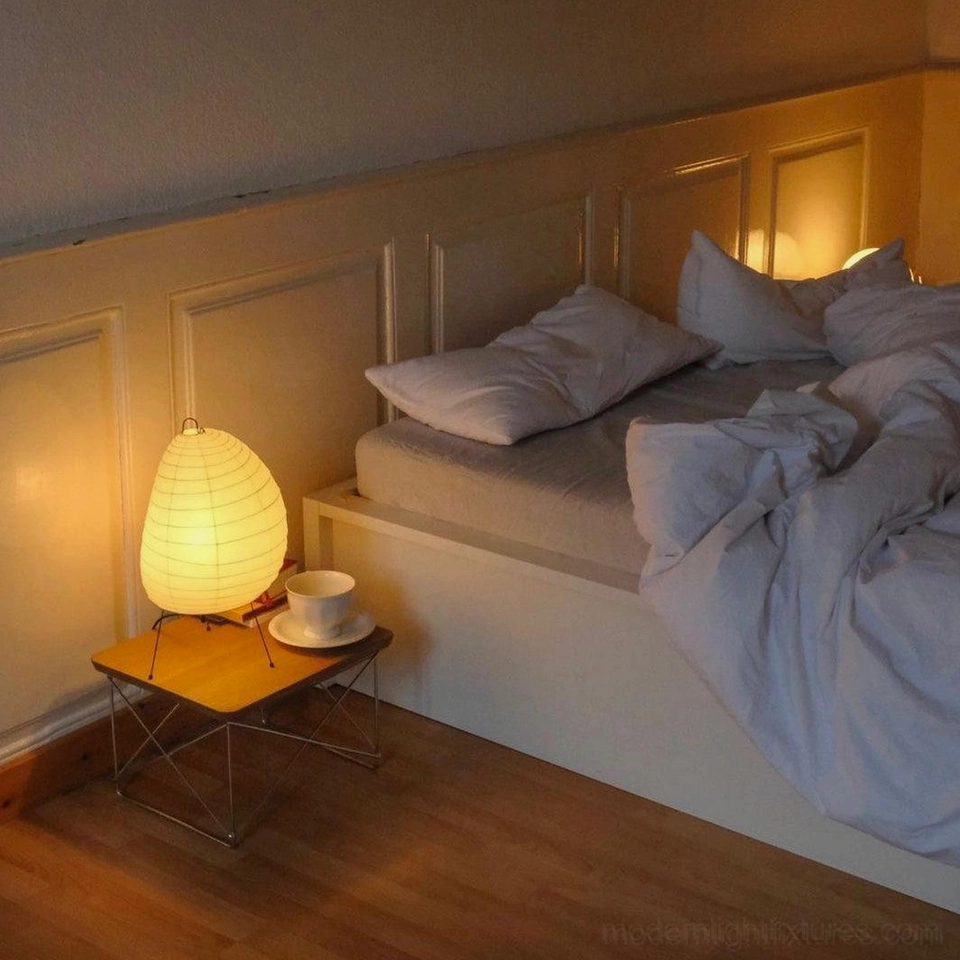 Akari 1N Japanese washi paper table lamp on wooden bedside table creating warm light in serene bedroom setting with coffee