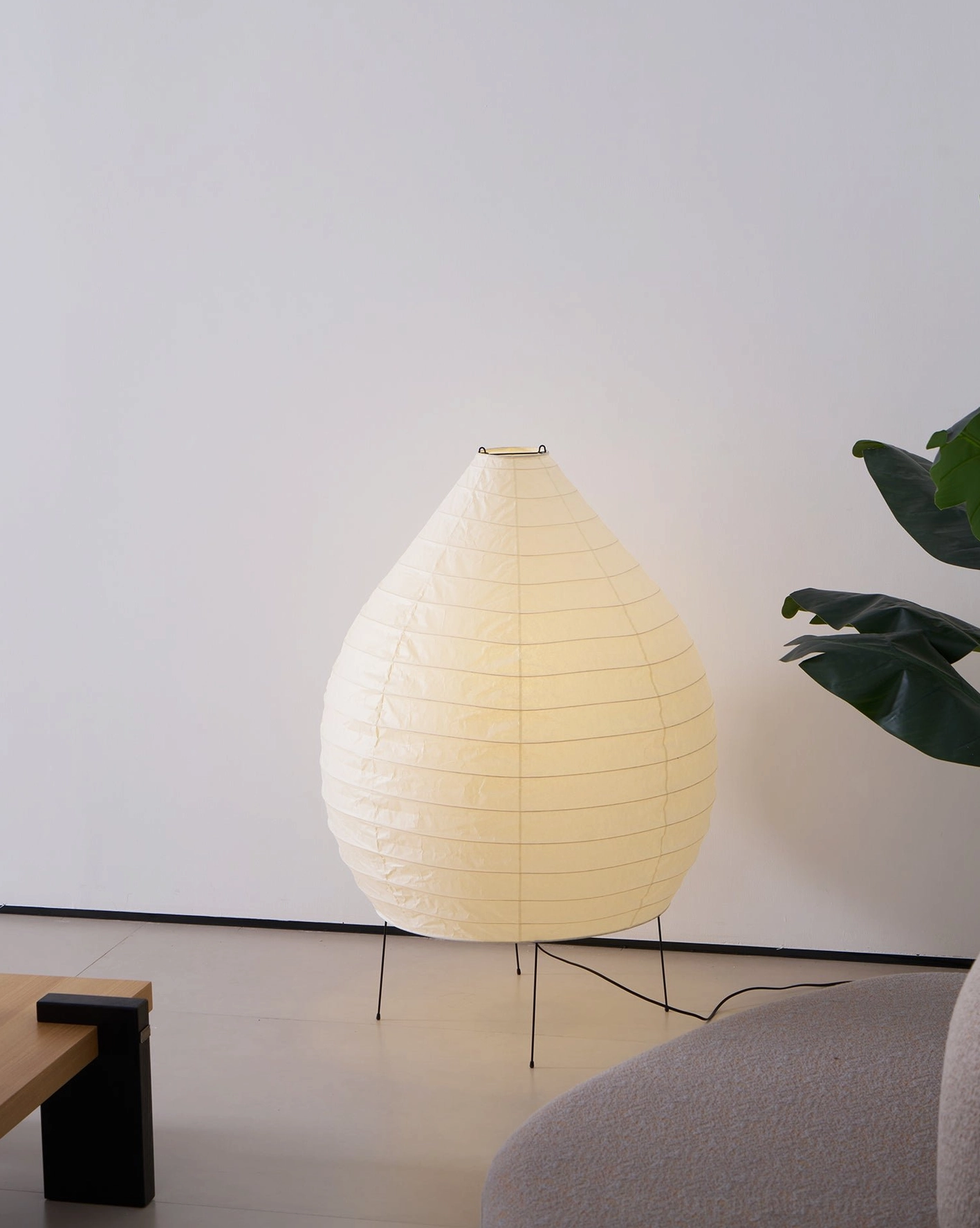 Akari 23N floor lamp side view in cozy minimalist living room with green foliage and bamboo frame