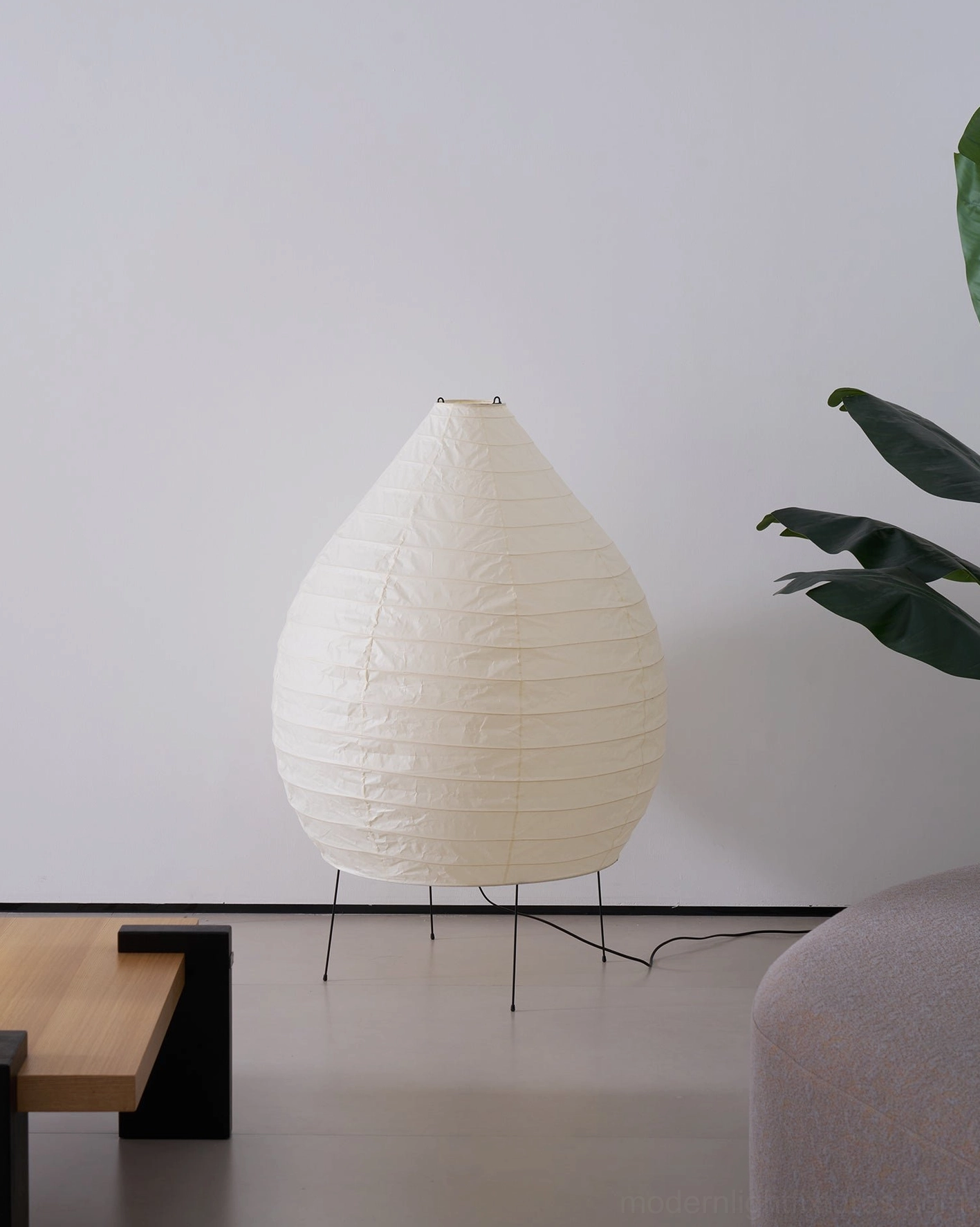 Akari 23N floor lamp three-quarter view in minimalist living space with side table and potted plant