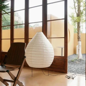 Akari 23N teardrop floor lamp three-quarter side view on residential patio with black metal tripod base