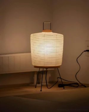 Akari 2A minimalist table lamp with unprinted pleated paper shade emitting warm ambient glow in residential bedroom setting