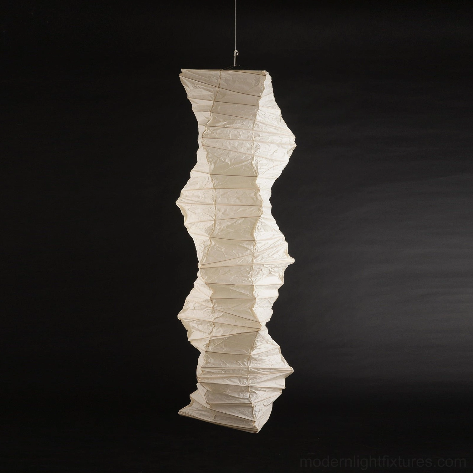Akari 33N tall folded paper pendant light front elevation on black background emphasizing cream-beige textured shade