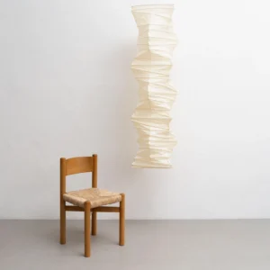 Akari 33N pendant lamp three-quarter side view in minimalist dining space with wooden chair showing off-white paper texture