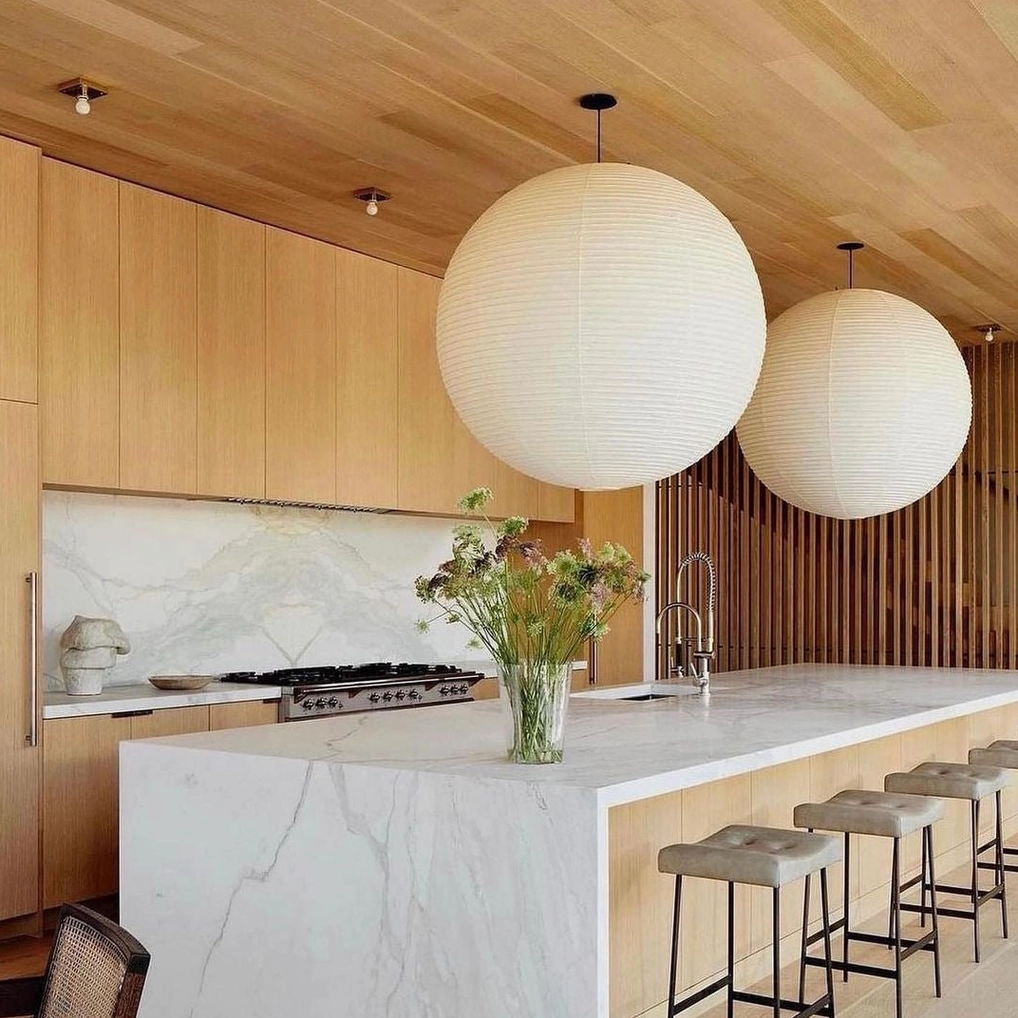 Dual Akari A white paper pendant lights above kitchen island with wood cabinetry