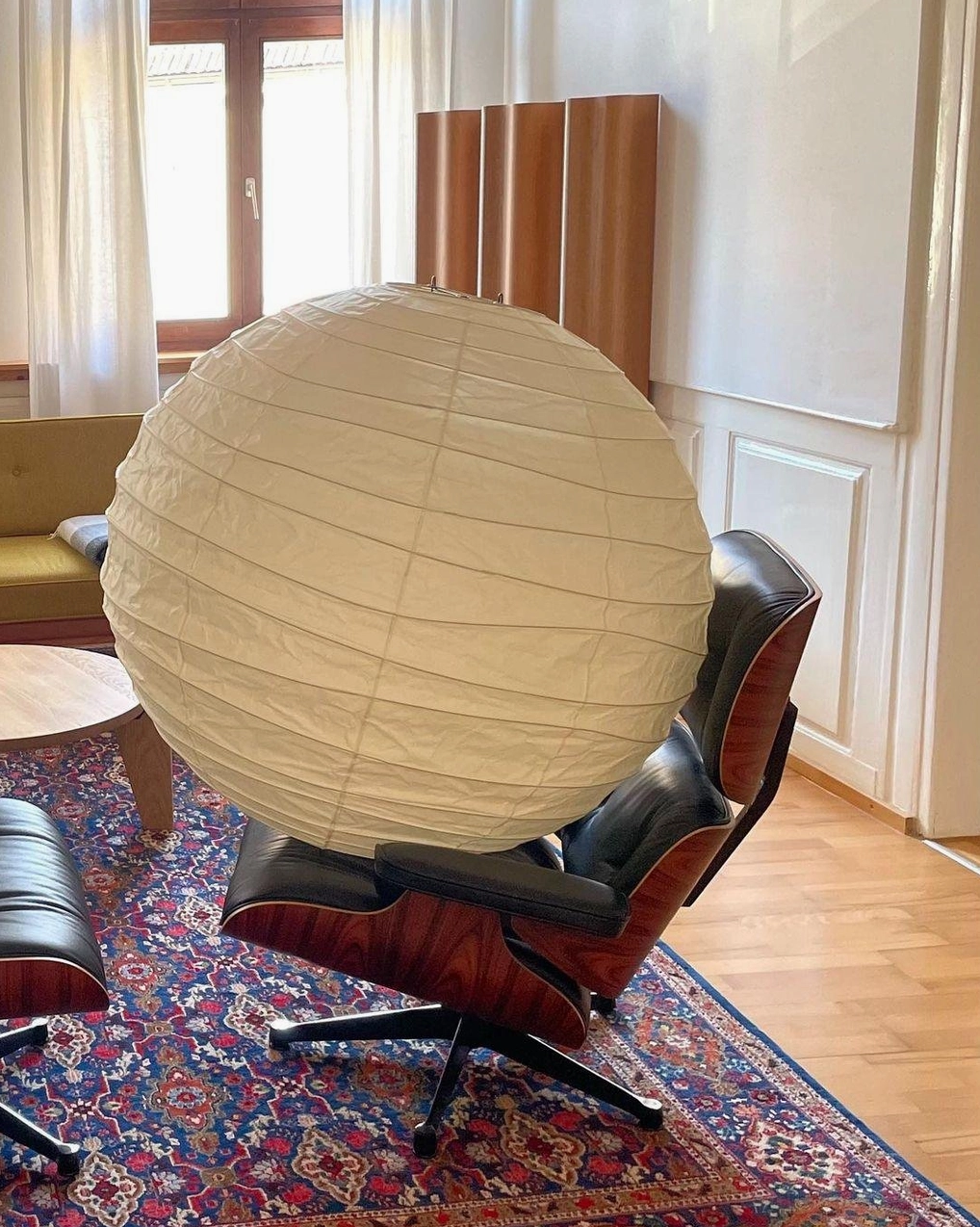 Modern Japanese pendant lamp in mid-century living room with classic lounge chair - three-quarter side view of 75cm size