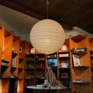 Japanese Washi pendant lamp installed in retro study with wooden bookshelf and dark ceiling - warm off-white paper diffusion