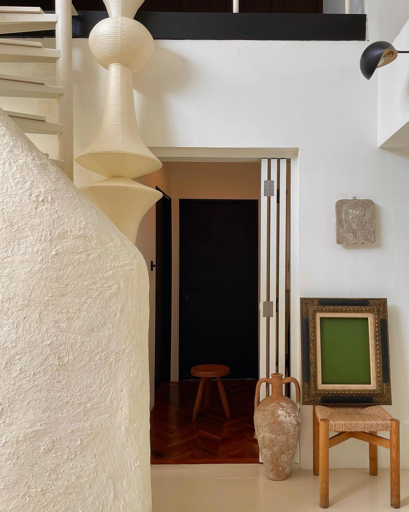 Akari E white paper pendant lamp hanging over home stairwell with off-white silhouette and wooden furniture
