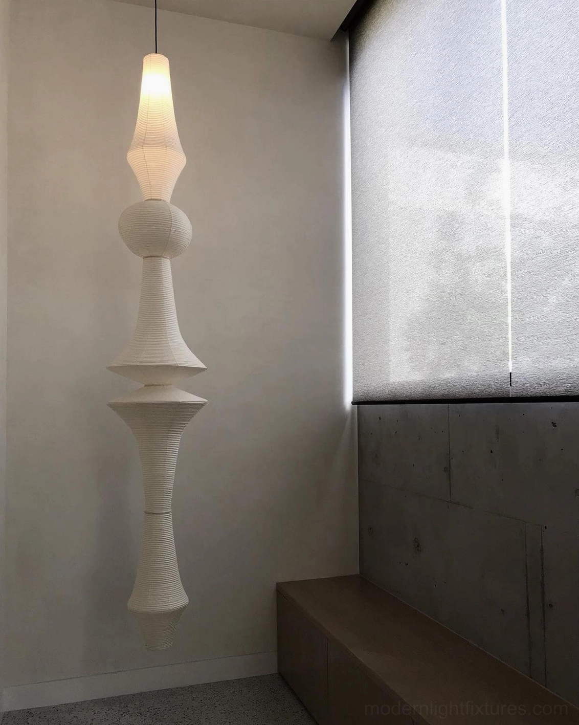 Small Akari E tapered white paper pendant lamp in minimalist home corner with soft warm light