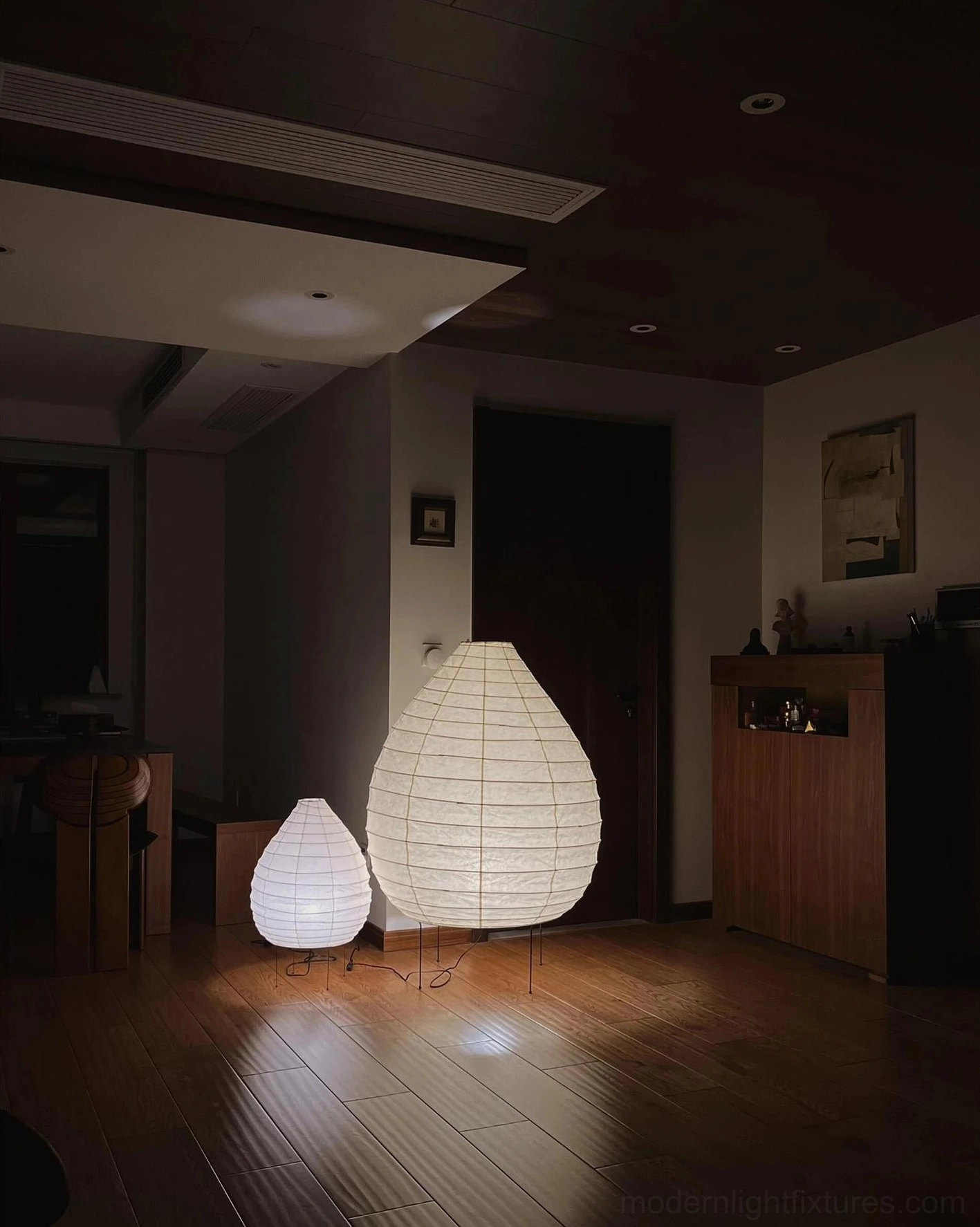 Two sizes of Akari teardrop floor lamps in warm lighting modern living room interior