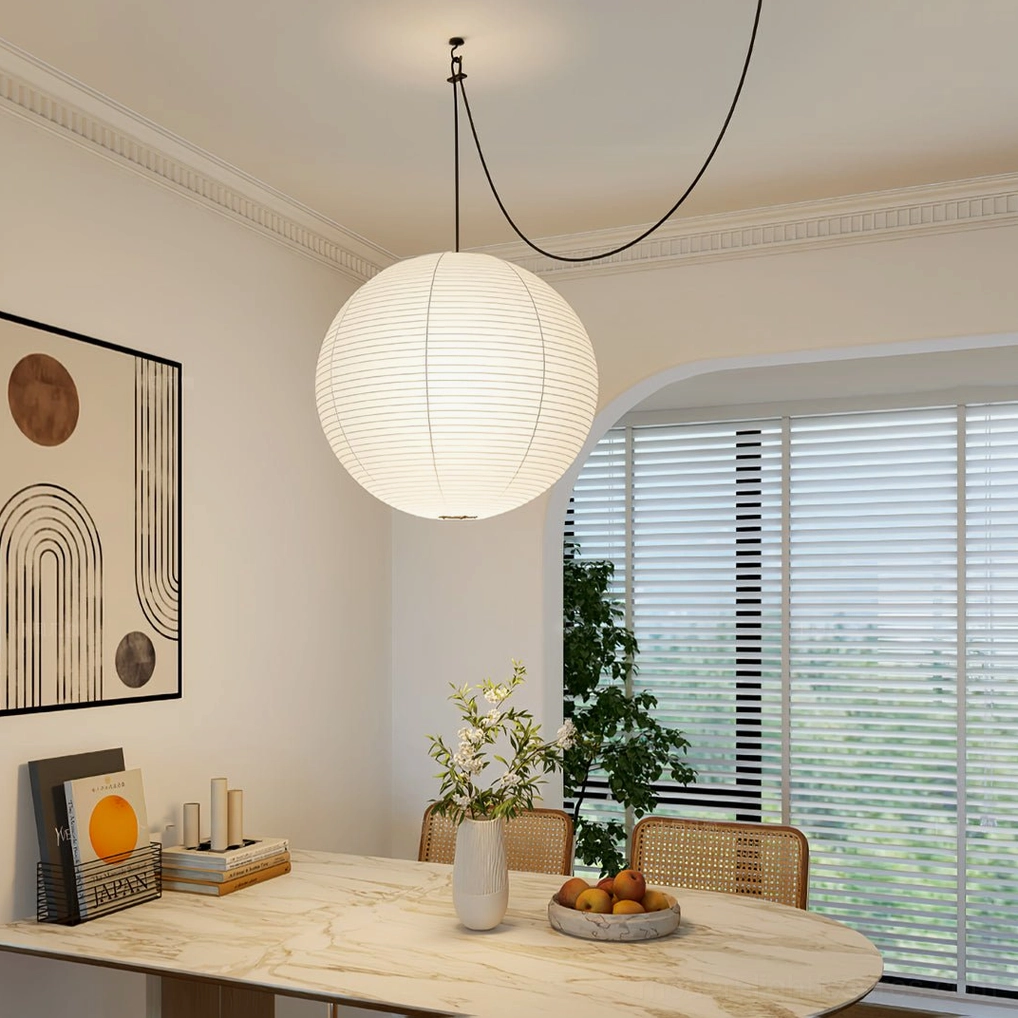 Akari paper pendant light with black cord above marble dining nook in warm minimalist style
