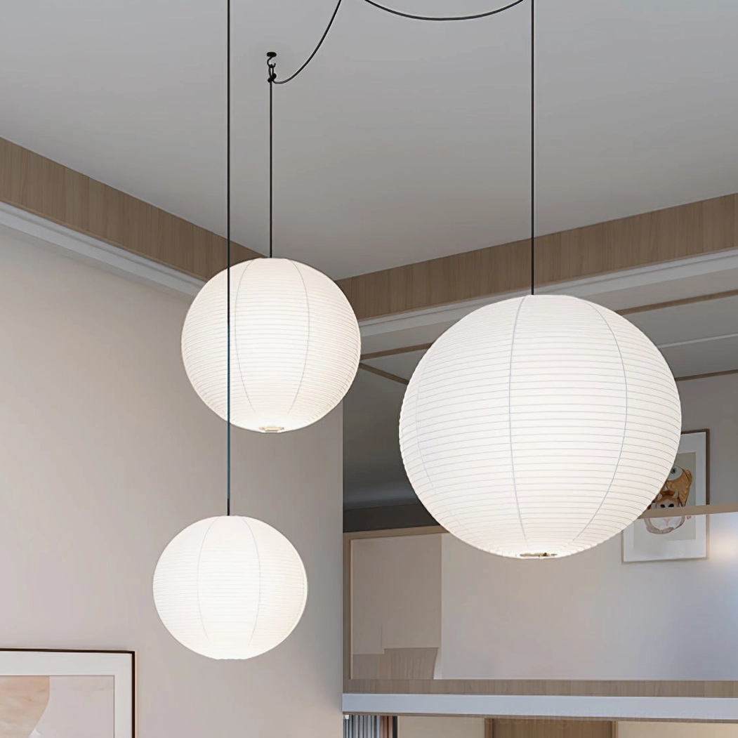Three Akari A Series paper pendant lamps in varying sizes above open-concept residential space