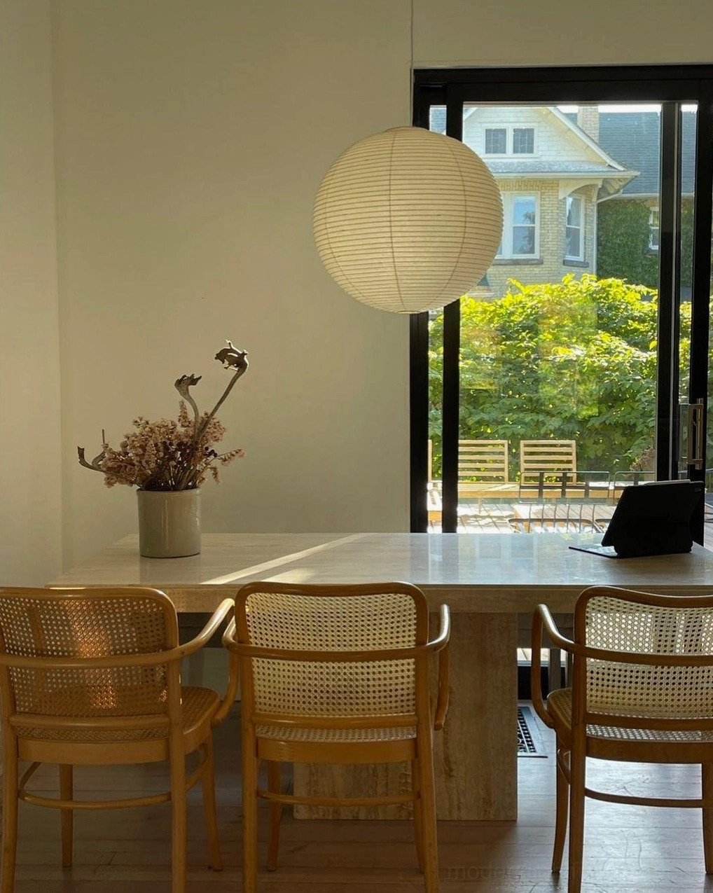 Akari A Series pendant lamp in bright dining space with garden view and rattan furniture