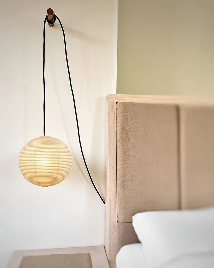 Akari paper pendant light with black plug-in cord mounted on interior wall corner