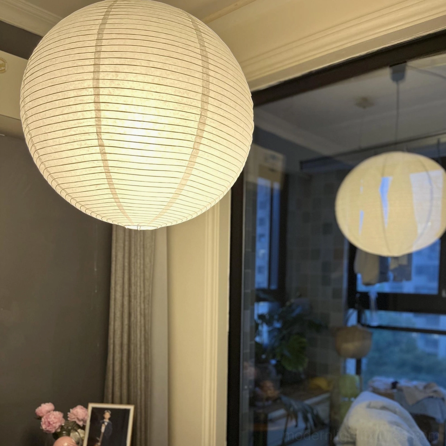 Close-up of glowing Akari Round pendant lamp with warm light filtering through handcrafted mulberry paper shade