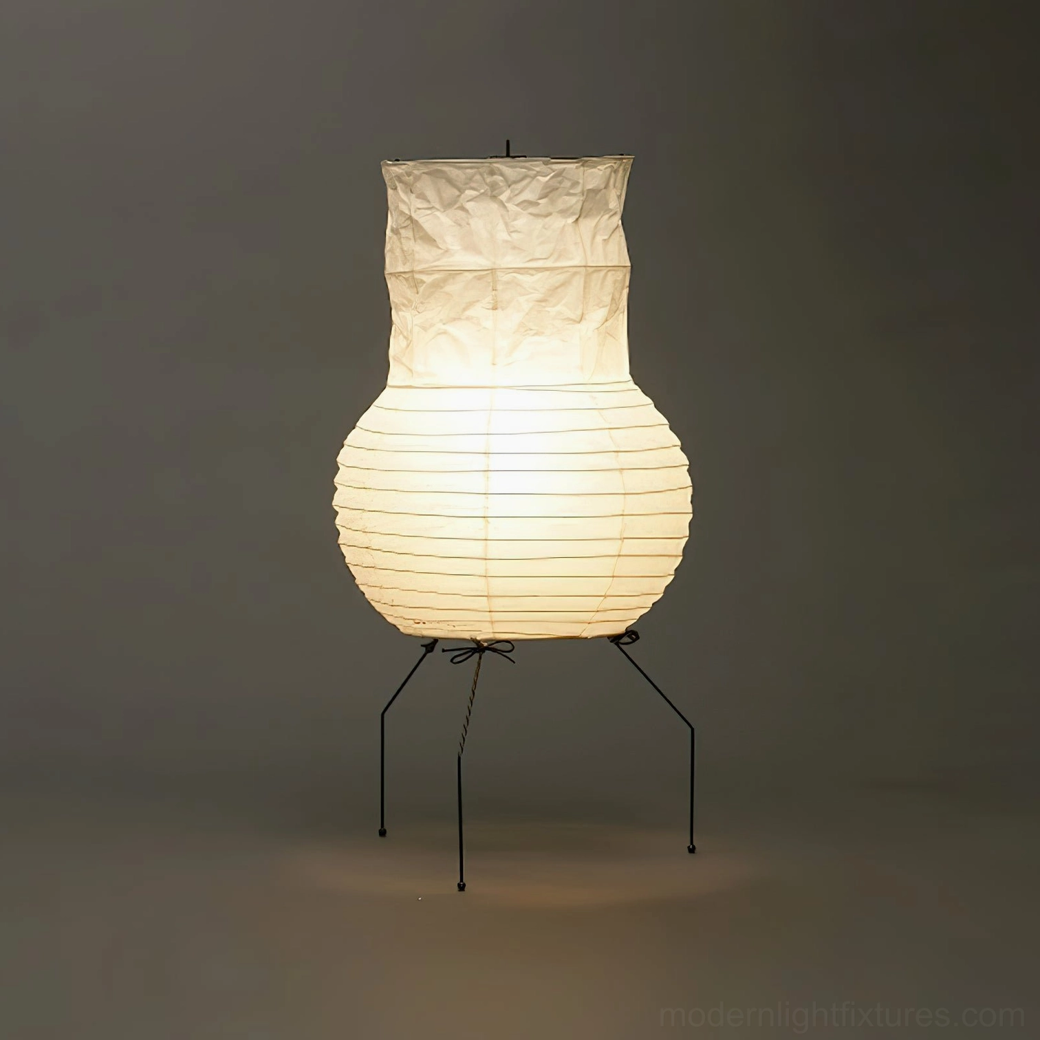 Akari UF1-S table lamp fully illuminated, front view showcasing ribbed crinkled paper shade with warm ambient lighting against dark background