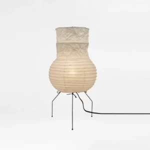 Akari UF1-S table lamp illuminated with warm soft glow, showing crinkled pleated paper shade detail, three-quarter view