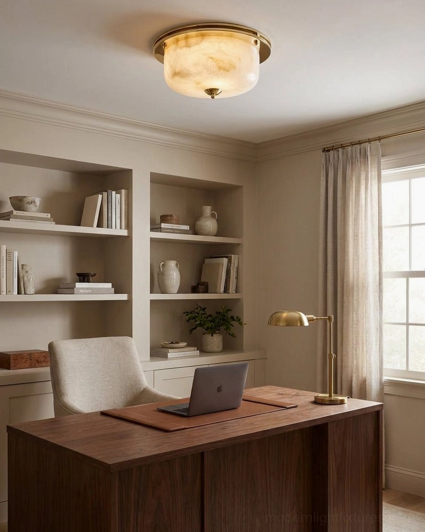 Justice polished brass and alabaster flush mount ceiling light in home office with wooden desk and built-in bookshelves