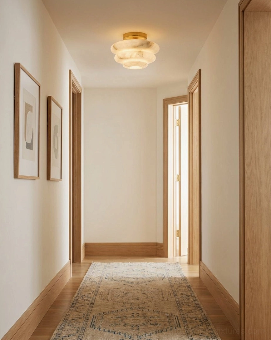 Alabaster flush mount ceiling fixture in hallway with framed art and area rug, low-profile light for corridors