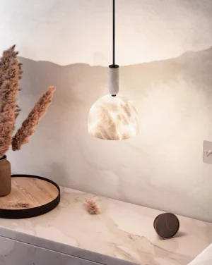 Warm glowing alabaster pendant light suspended above bedroom vanity table with dried floral decor