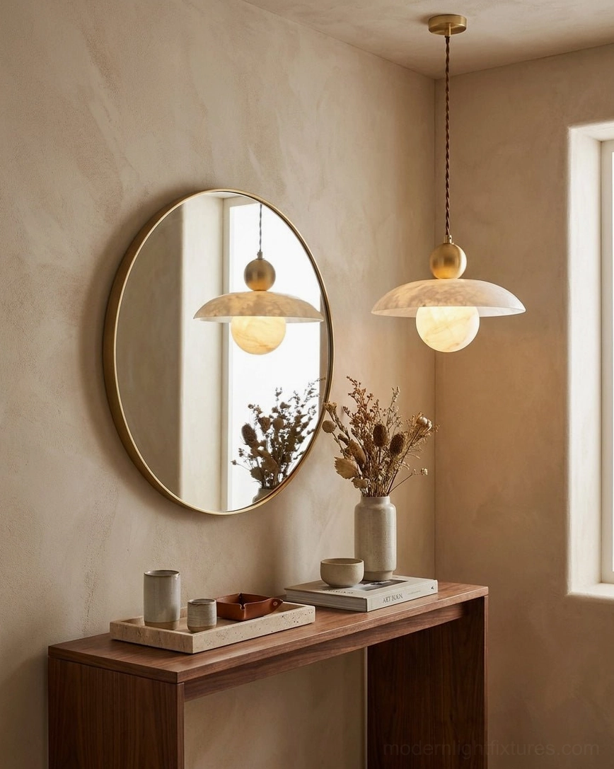 Alabaster pendant light suspended above console table entryway with round mirror reflection and sculptural design