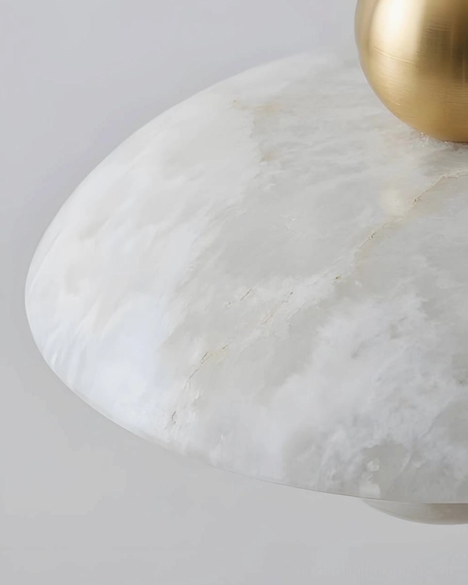 Alabaster pendant light illuminated overhead view showing saucer and orb stone pieces glowing with soft ambient light