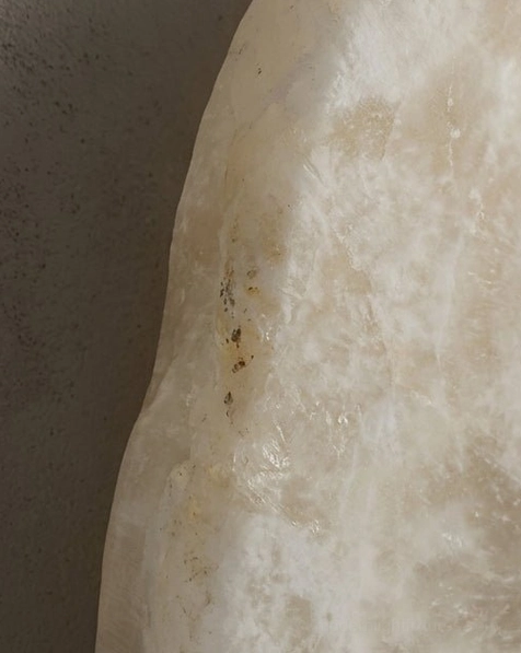 Hand-cut alabaster wall sconce with integrated LED backlight, warm white glow through natural stone