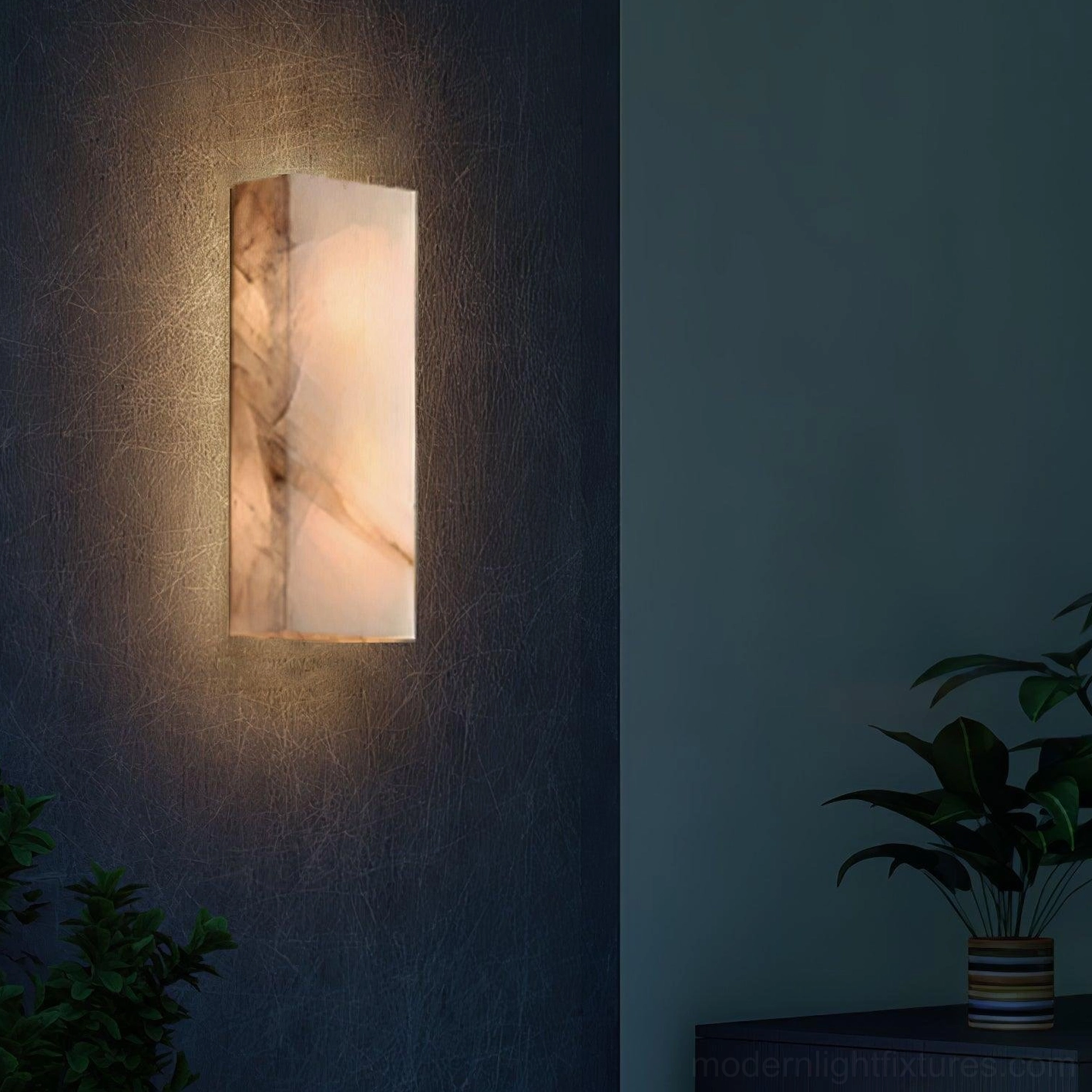 Alabaster wall sconce illuminated corner green plants warm glow dark wall ambient lighting