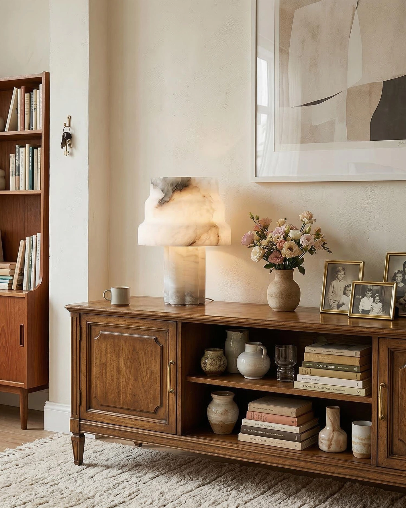 Modern alabaster table lamp on living room side cabinet with warm wooden furniture and neutral home decor
