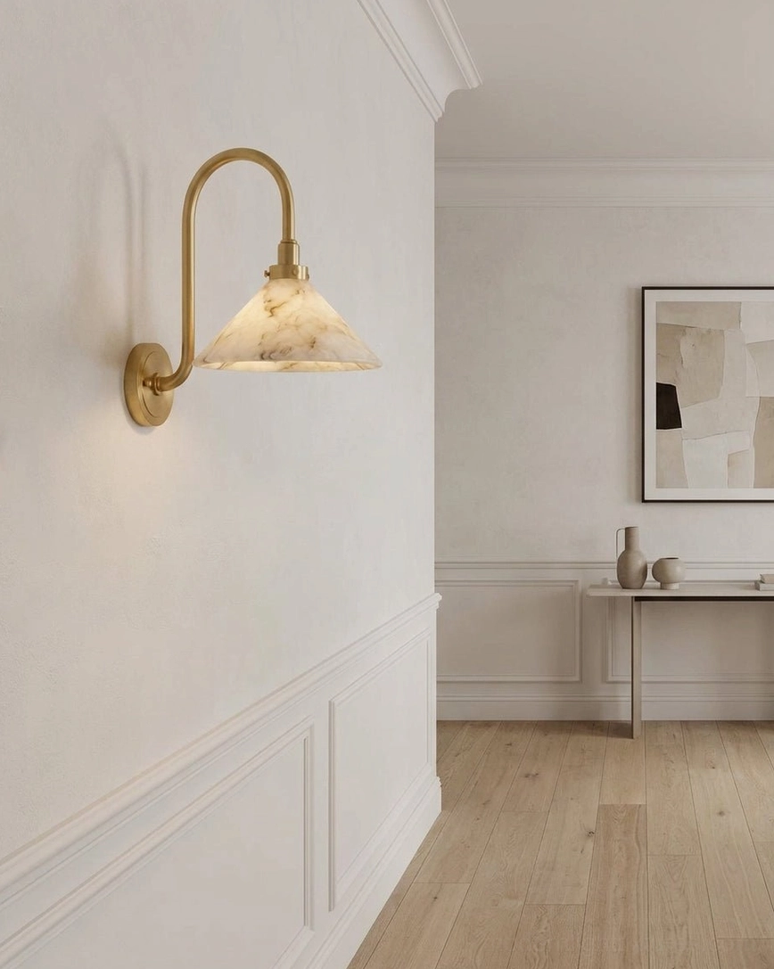Lunelle wall sconce in residential hallway with wainscoting, brass arm and stone shade architectural detail