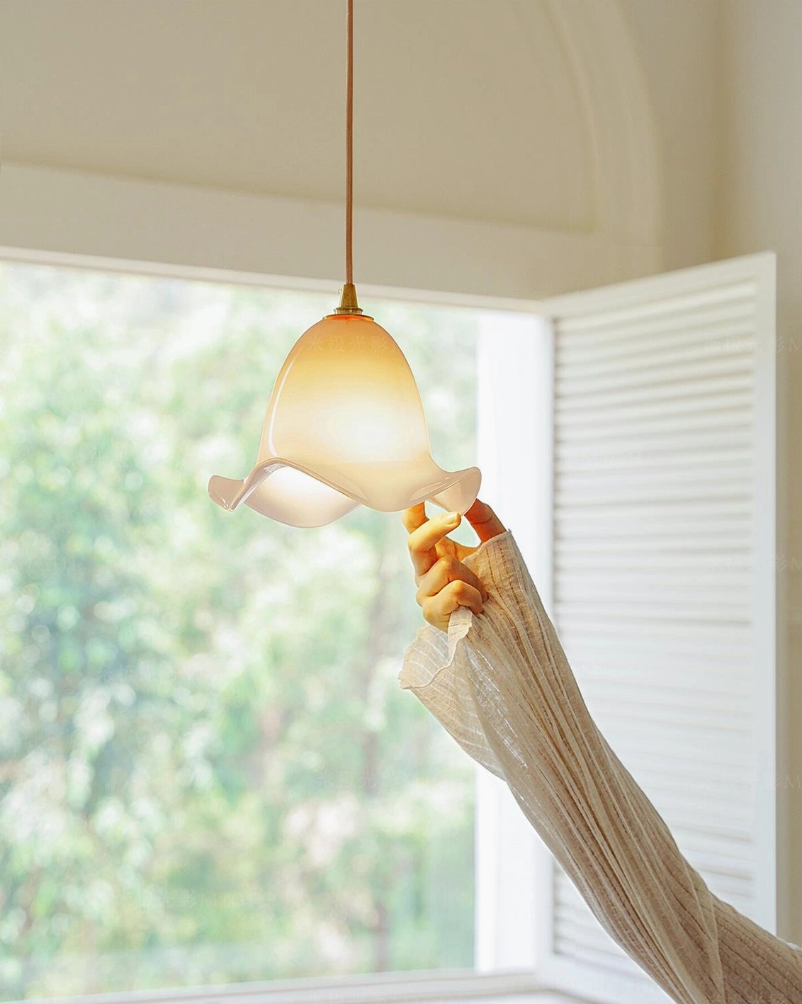 Illuminated Aluna glass pendant lamp glowing warm light, side view showing ruffled organic glass texture