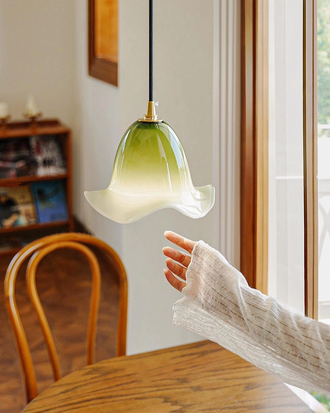 Matcha green Aluna hand-blown glass pendant in vintage wooden dining room setting, three-quarter angle view