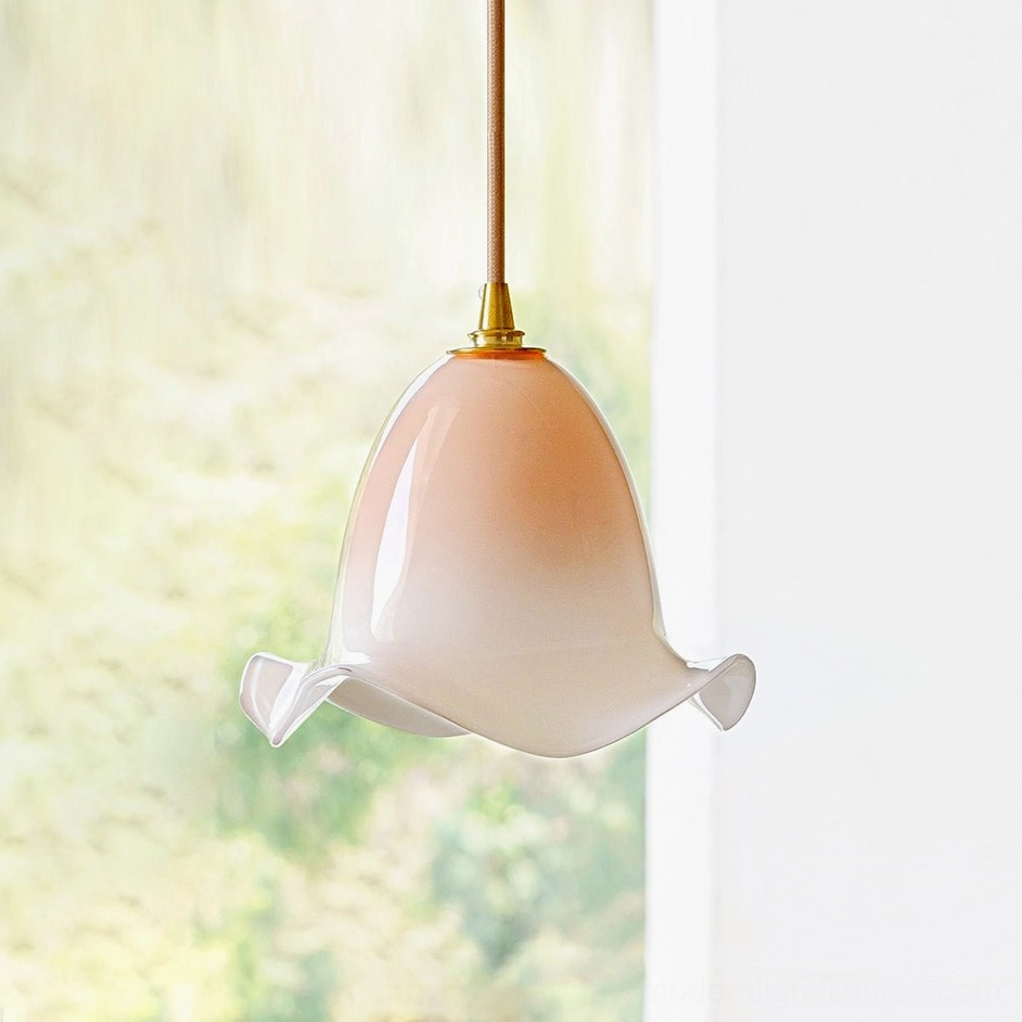 Blush pink Aluna hand-blown pendant light with ruffled glass shade, natural daylight view with foliage backdrop