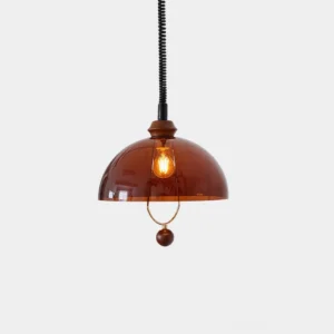 Amber dome pendant light with translucent glass shade, brass ring accent and wooden sphere detail, vintage bulb visible on white wall