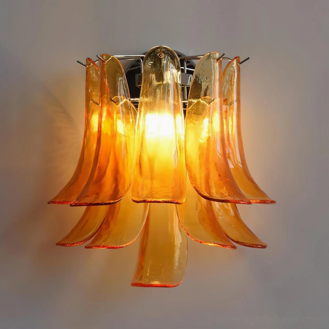 Amber flower petal wall sconce with illuminated warm interior glow, high angle view of glossy textured glass petals
