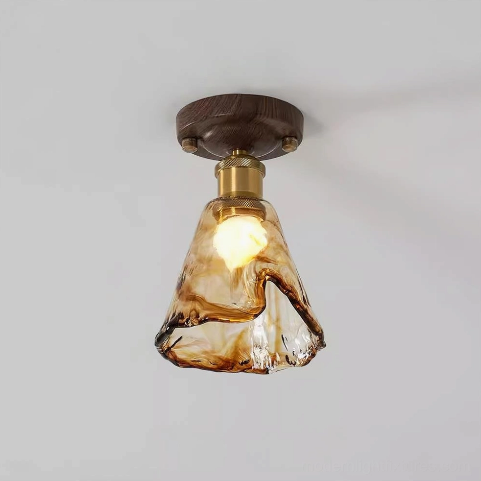 Illuminated nalia amber ceiling light showing warm glow through textured glass with polished brass connector details on studio backdrop