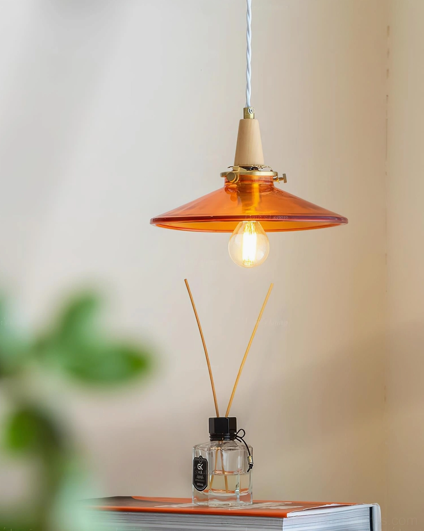 Close-up side view of amber glass pendant light showing brass-toned fixture and translucent glass details