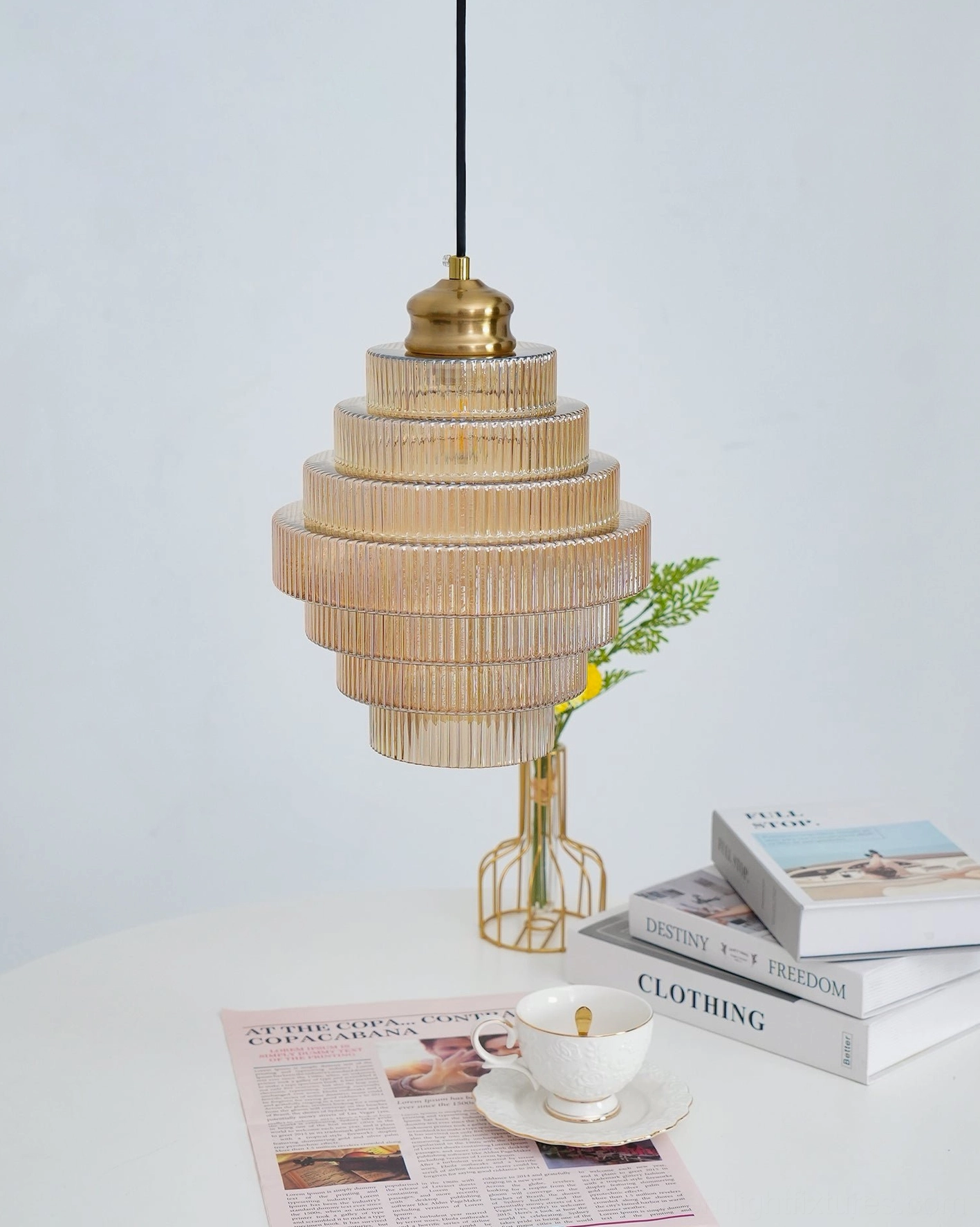 Amber glass pendant light over white round dining table with tableware and floral arrangement