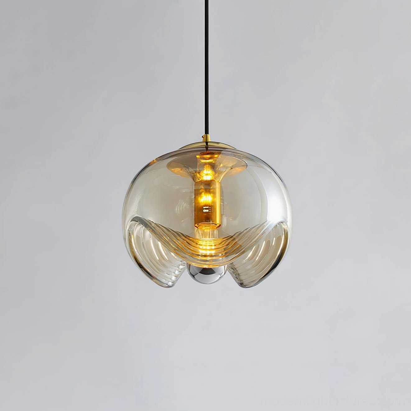 Warm amber-tinted globe glass pendant light studio overhead shot, showcasing textured glass shade with gold-toned metal fixture