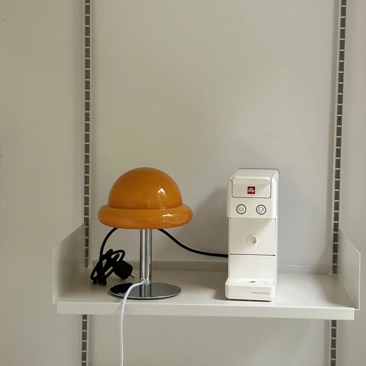 Amber glass mushroom lamp on floating wall shelf with desk accessories and water dispenser