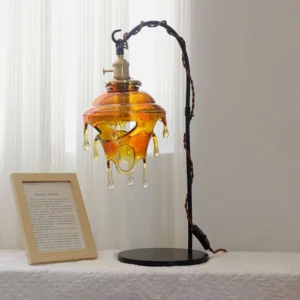 Amber resin drip table lamp three-quarter side view on linen tablecloth, warm honeyed resin glow