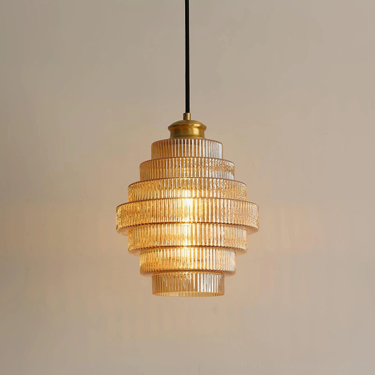 Amber ridged glass pendant light illuminated, casting warm refracted light patterns on wall