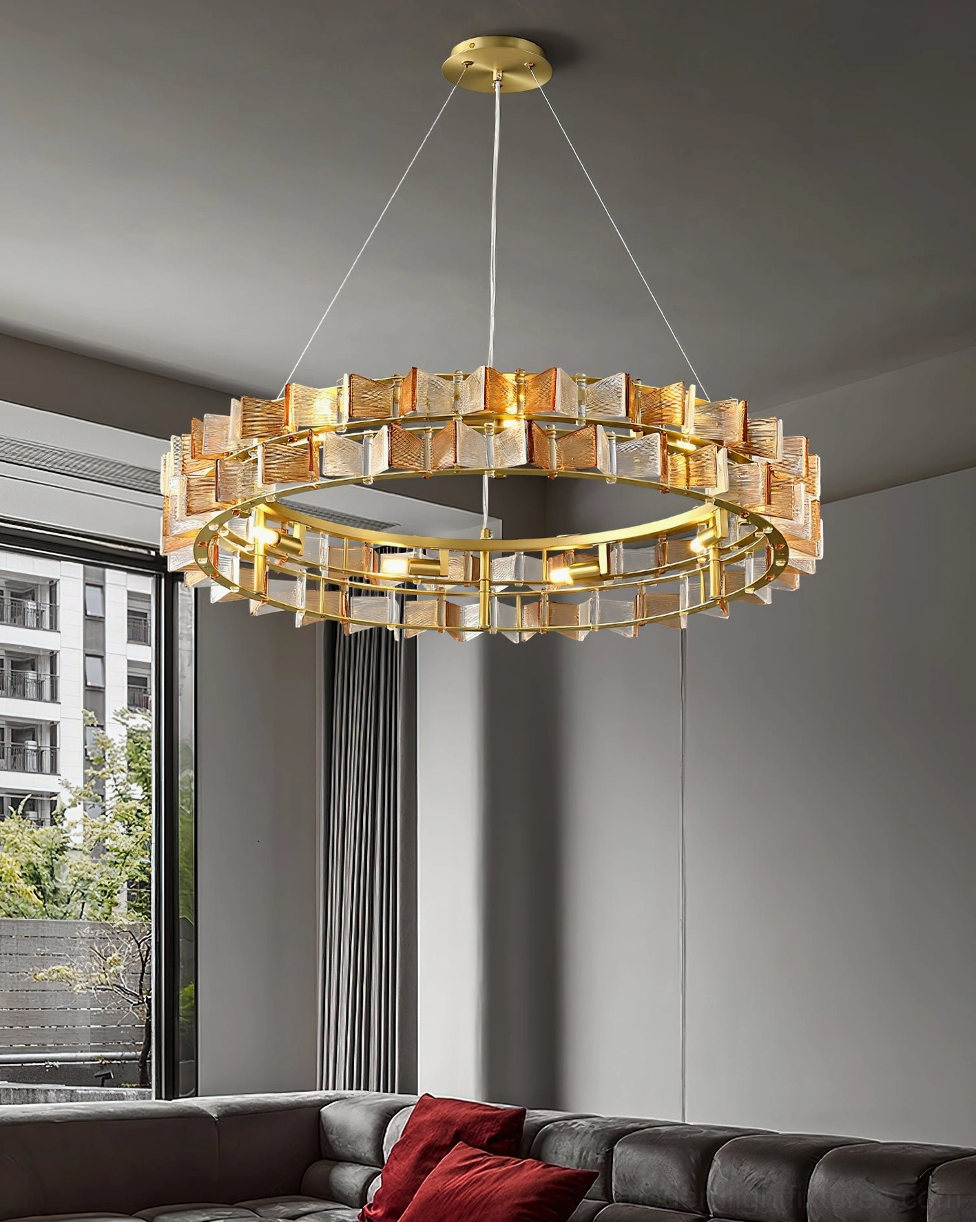 Amber glass ring chandelier installed in modern living room with dark sofa, warm ambient lighting