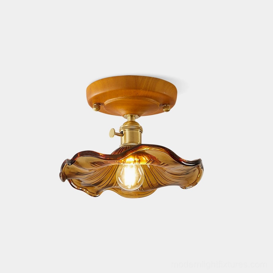 Amber ruffled glass flush mount ceiling light with wood canopy and brass fixtures, front view on white background